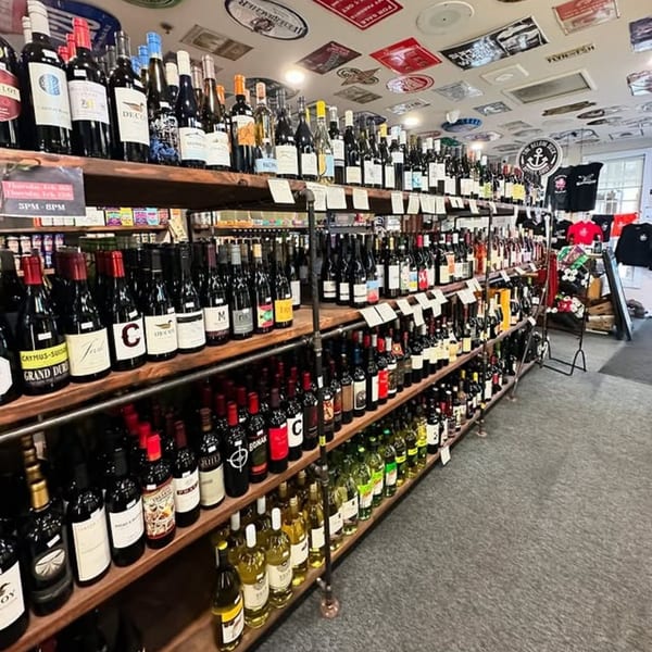 A wide selection of red and white wine bottles displayed on wooden shelves in a store.