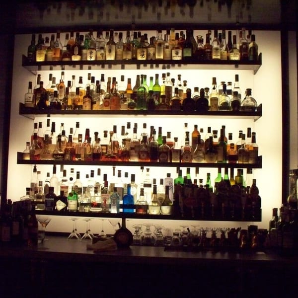 A dimly lit bar at Flanigan's Boathouse with shelves of liquor bottles and glassware.