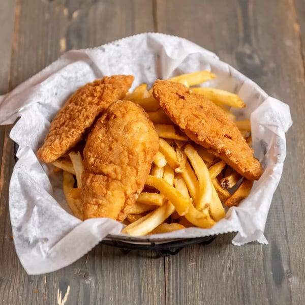 A black basket lined with white paper holds golden-brown fried chicken tenders and french fries.
