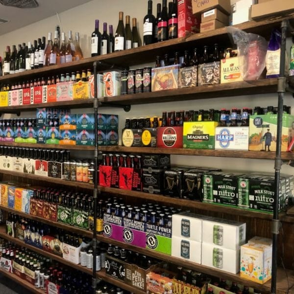 A large wall of wooden shelves filled with various bottles and cases of beer and wine.