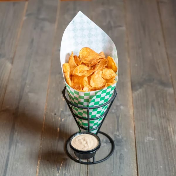 Crispy golden potato chips in a green and white checkered paper cone with a side of dipping sauce.