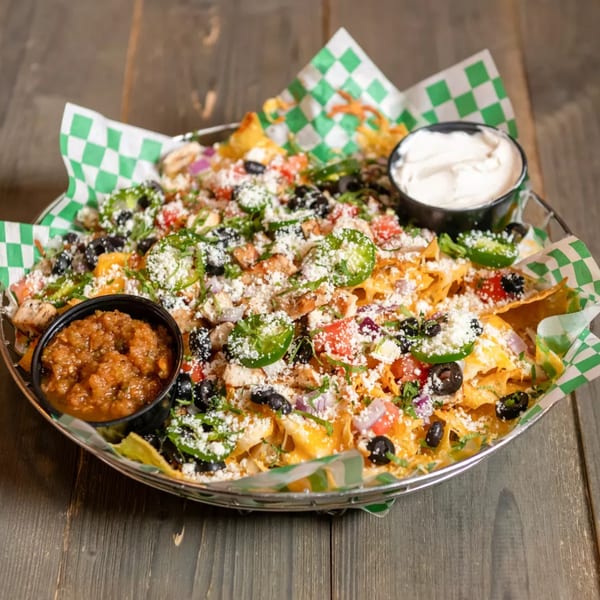 Loaded nachos with chicken, black olives, jalapeños, cheese, salsa, and sour cream.