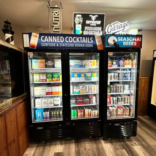 Three glass-front refrigerators filled with various canned cocktails and seasonal beers at Flanigan's Boathouse.