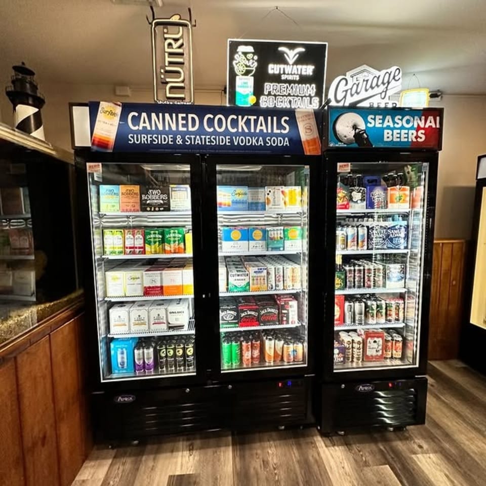 Three glass-front refrigerators filled with various canned cocktails and seasonal beers at Flanigan's Boathouse.