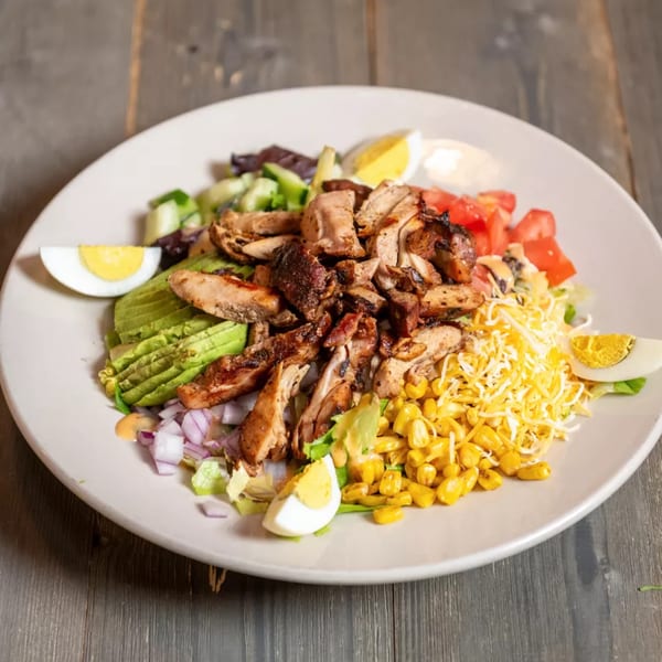 Grilled chicken salad with avocado, corn, tomatoes, cheese, red onion, and hard-boiled eggs.