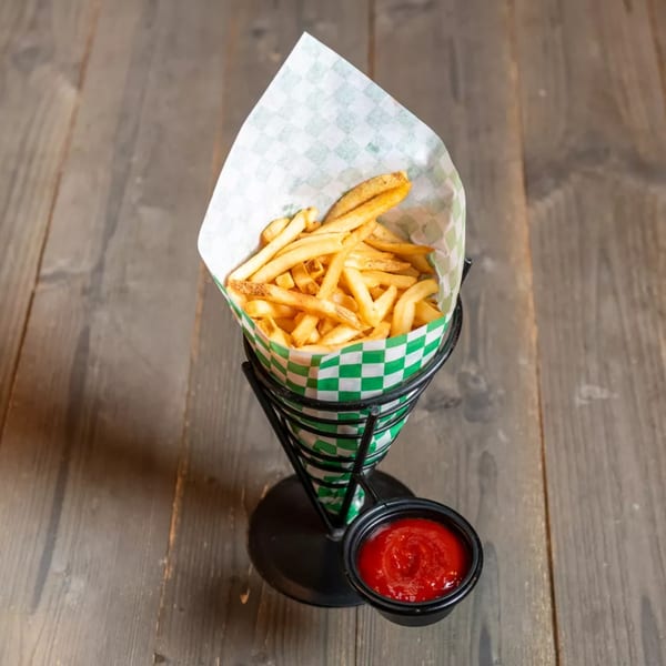 Golden french fries in a green and white checkered paper cone with a side of ketchup.